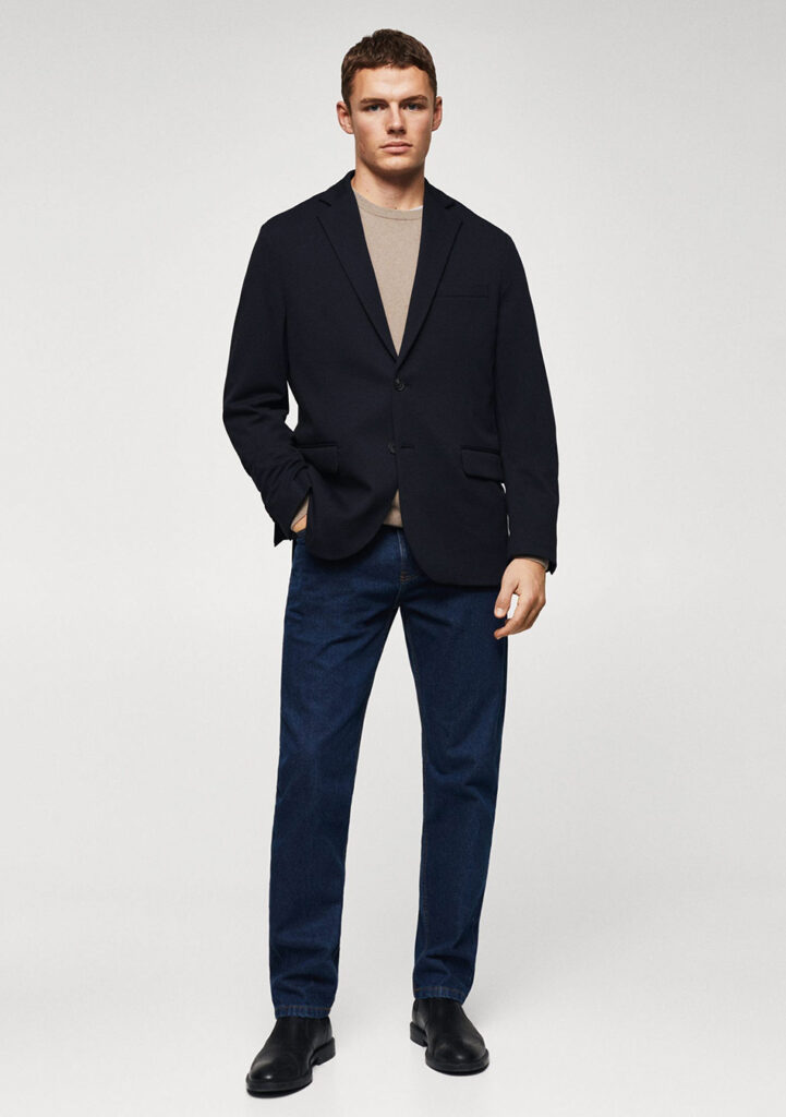 Black blazer, tan sweater, navy jeans, and black Chelsea boots