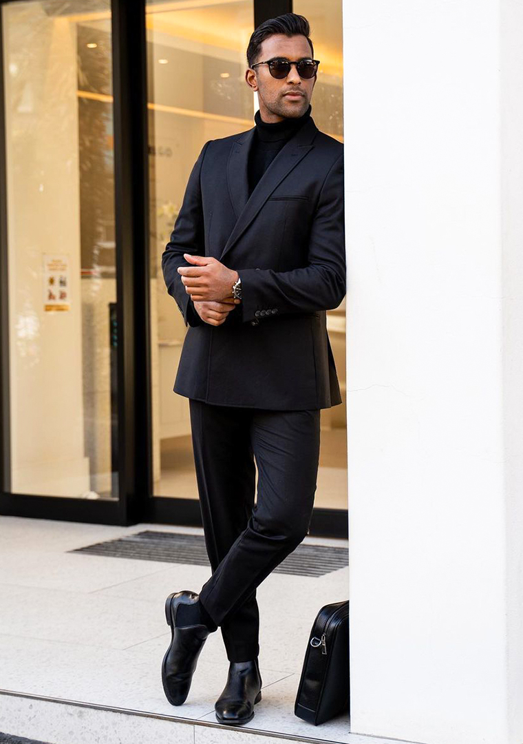 Black suit, black turtleneck, and black Chelsea boots