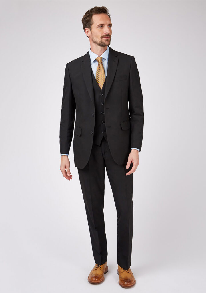 Black three-piece suit, blue shirt, brown tie, and brown brogue shoes