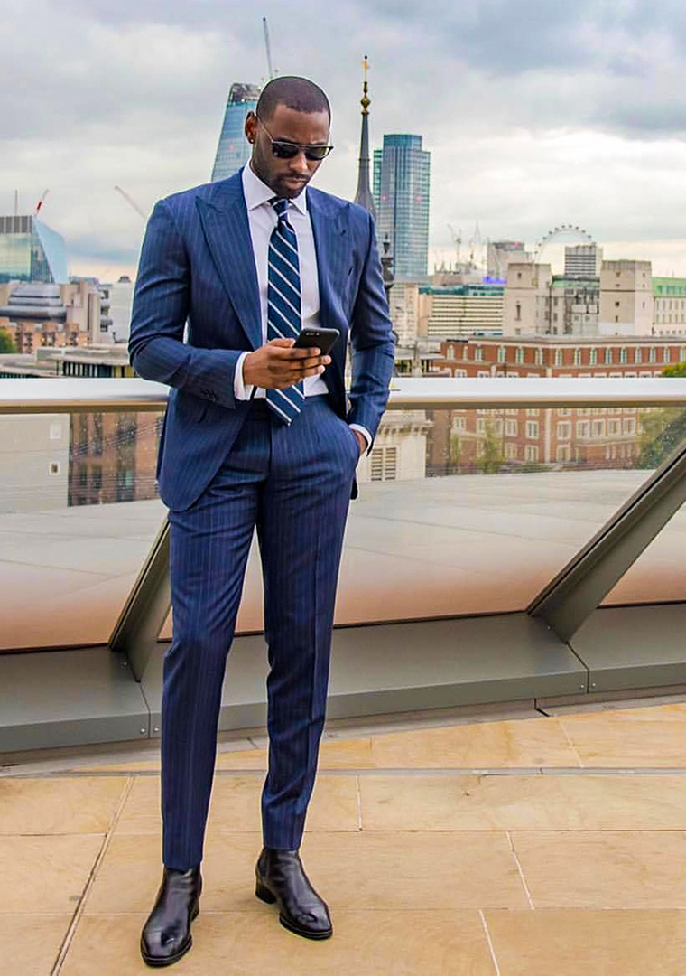 Blue pinstripe suit, white dress shirt, navy striped tie, and black leather Chelsea boots