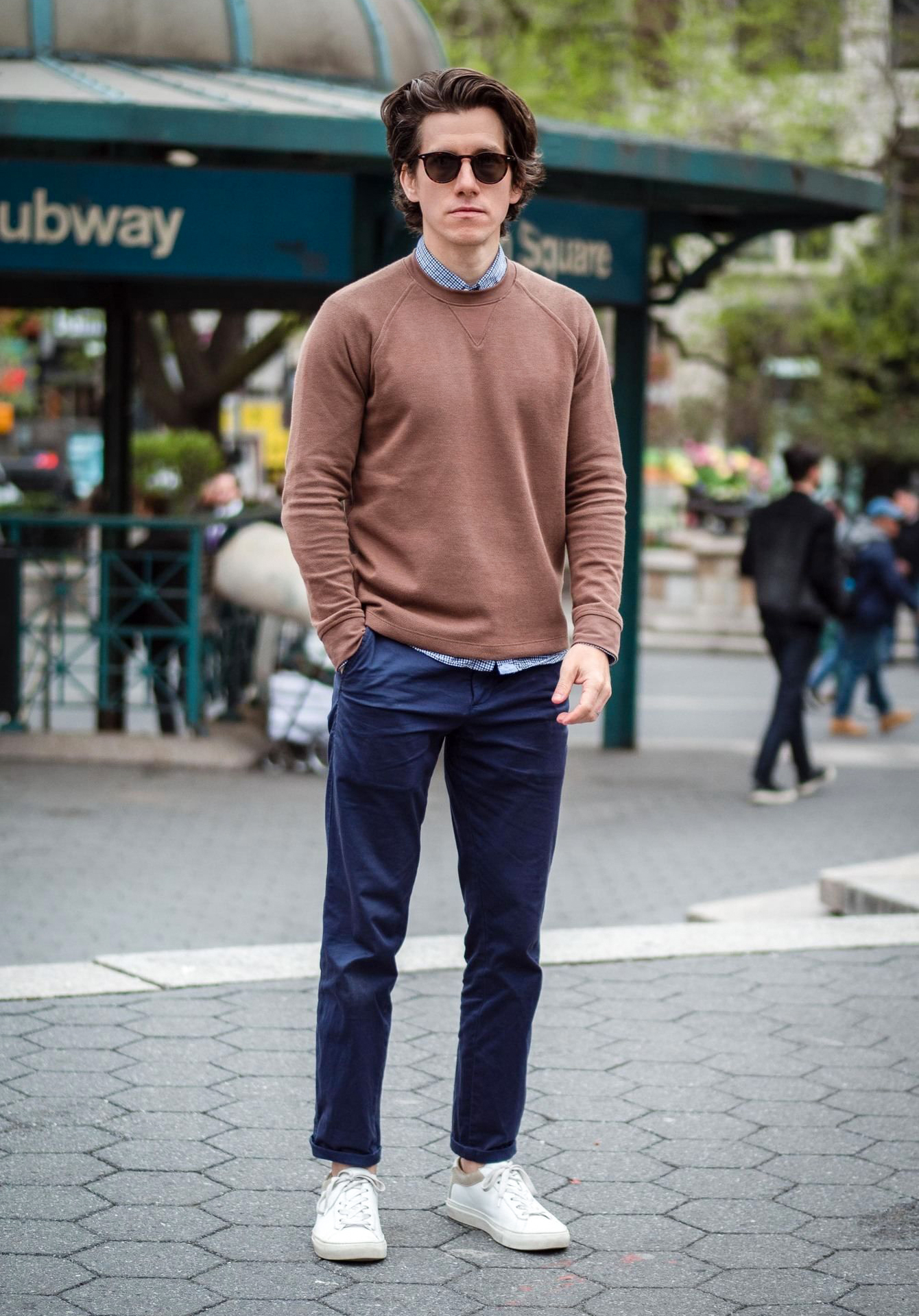 Brown sweater, blue button-down shirt, navy pants, and white shoes
