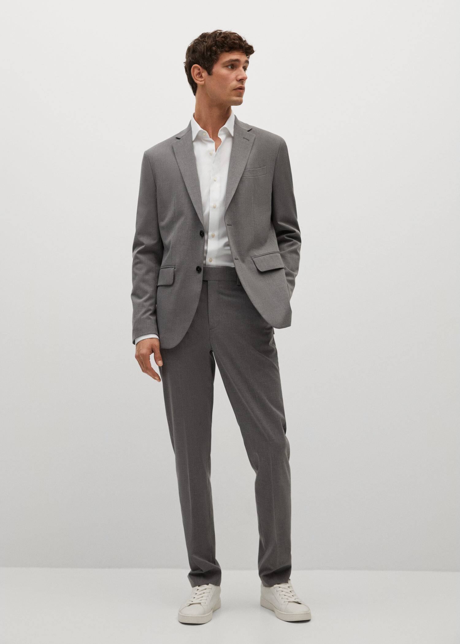 wearing a grey cotton suit with a white shirt and white sneakers