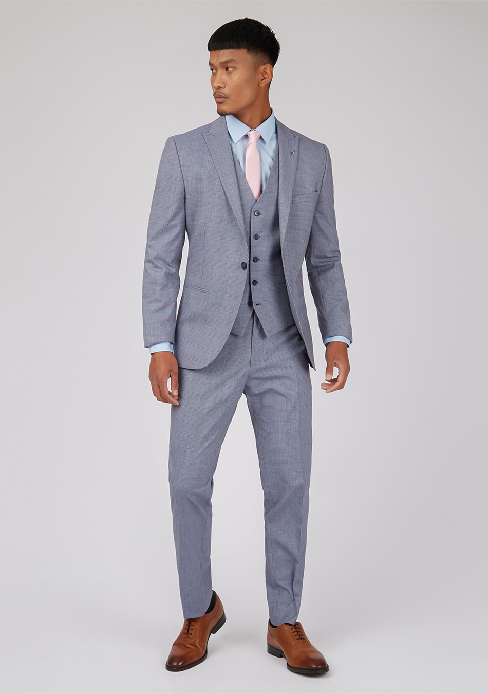 Grey three-piece suit, blue dress shirt, pink tie, and brown Oxford shoes