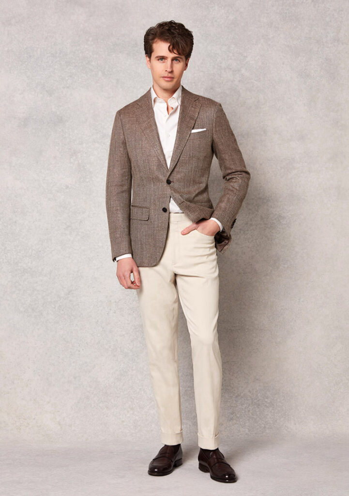 Young stylish Caucasian man wearing white shirt and beige pants, standing  on the street on beautiful ancient European city background, smiling to  Stock Photo - Alamy