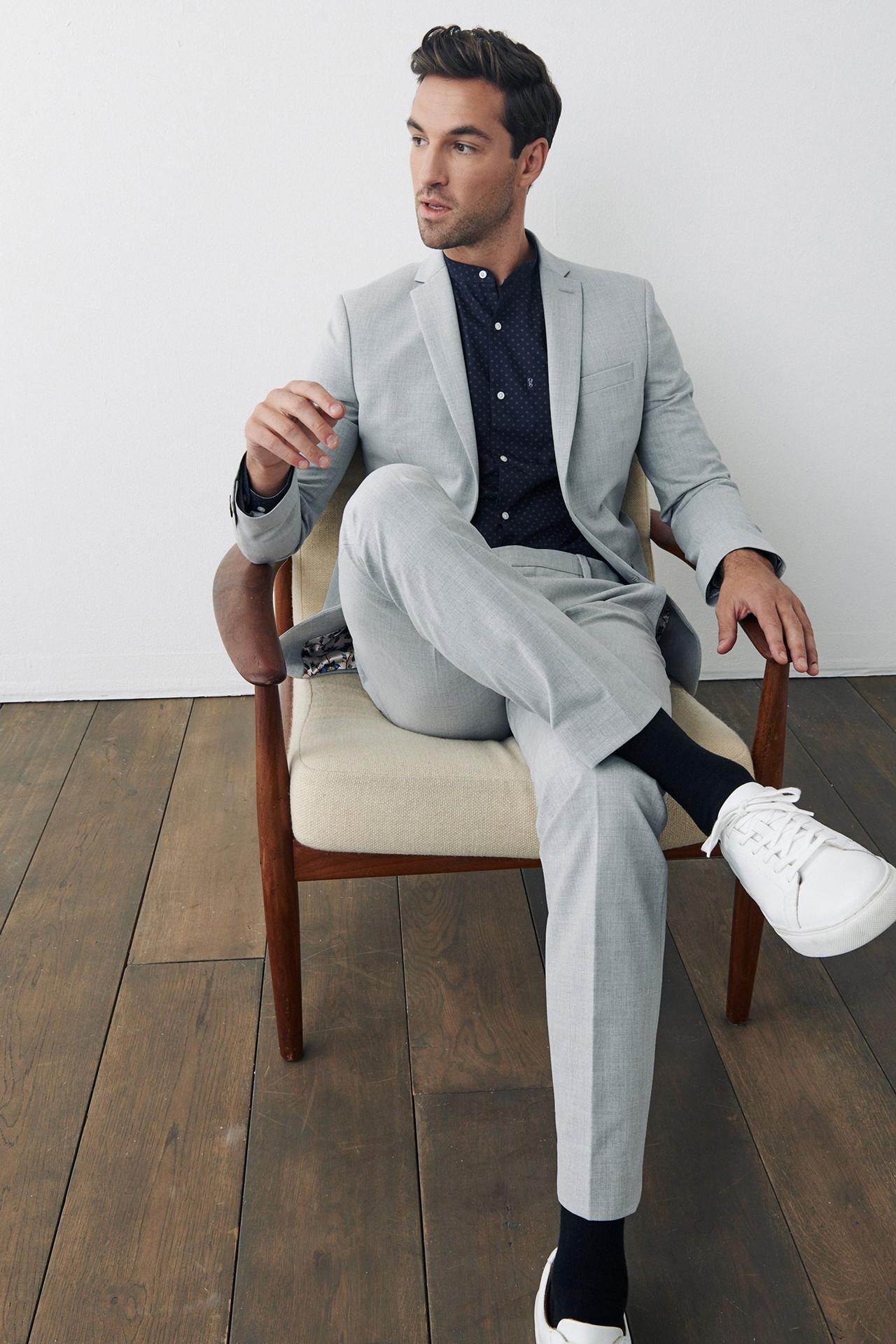 White sneakers with a light grey suit and black patterned shirt