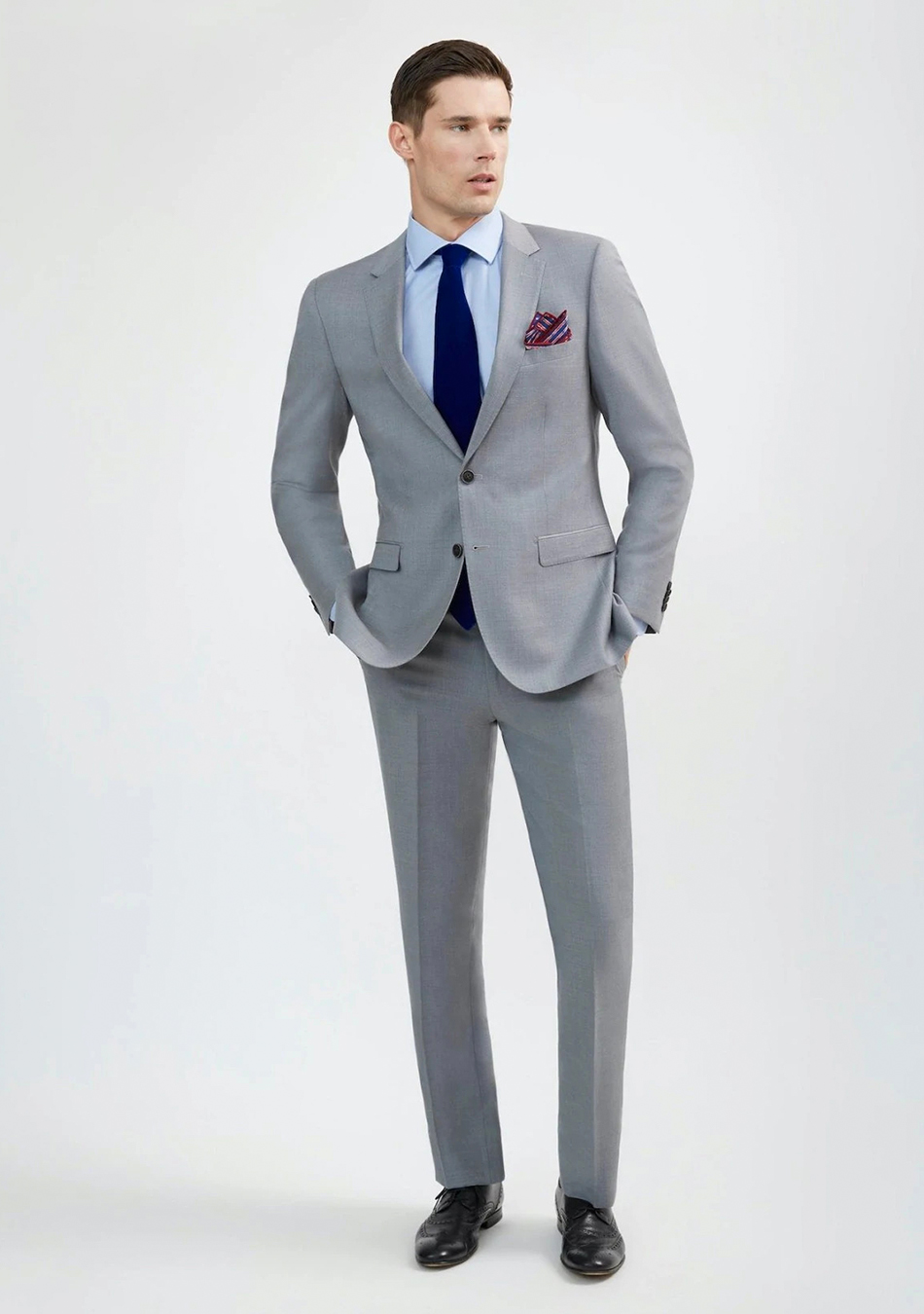 Light grey suit, blue shirt, navy tie, and black derby shoes