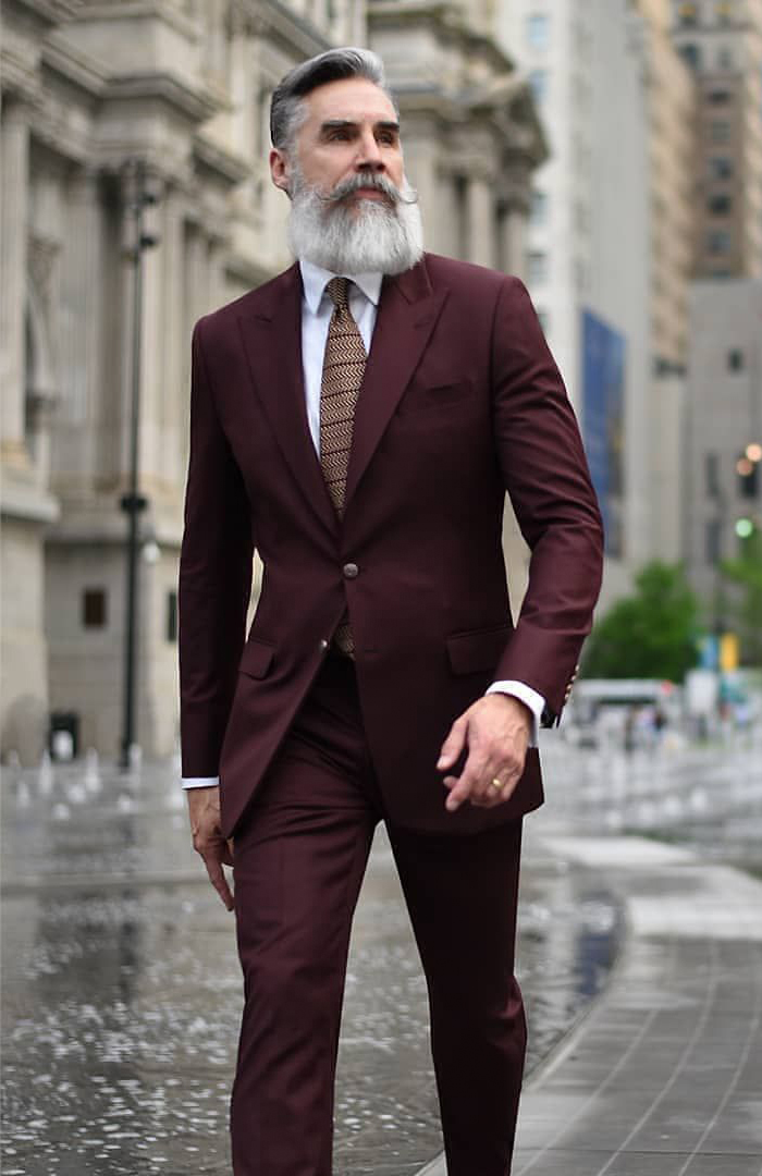 Maroon suit with a white dress shirt and brown striped tie