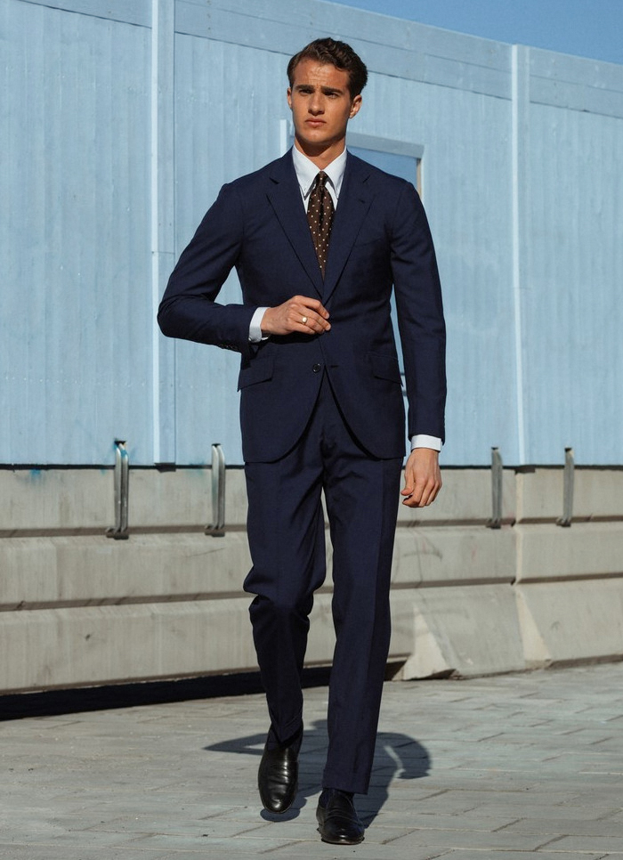 Navy suit with white shirt, brown tie, and black penny loafers