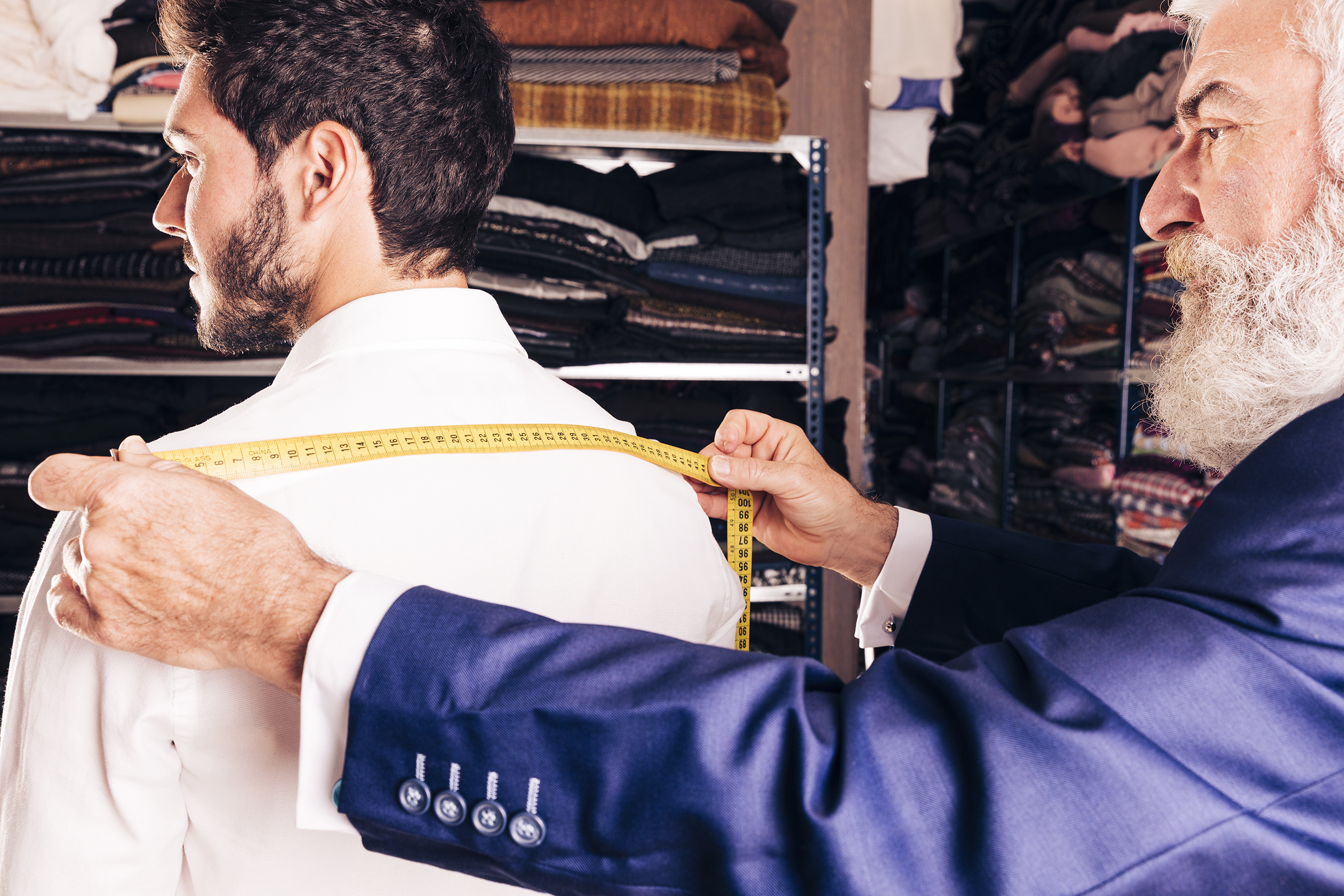 Tailor taking the suit jacket shoulder width measurement