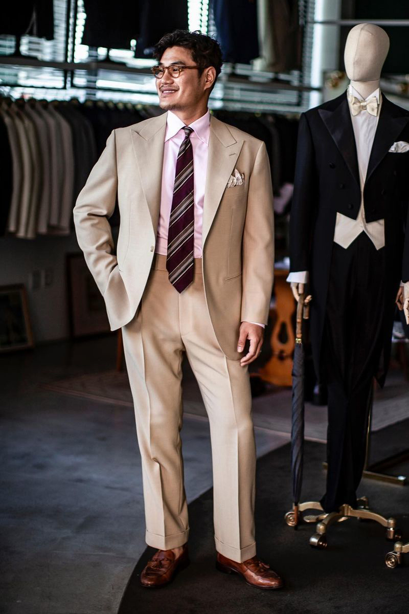 Tan suit, light pink shirt, and red striped tie