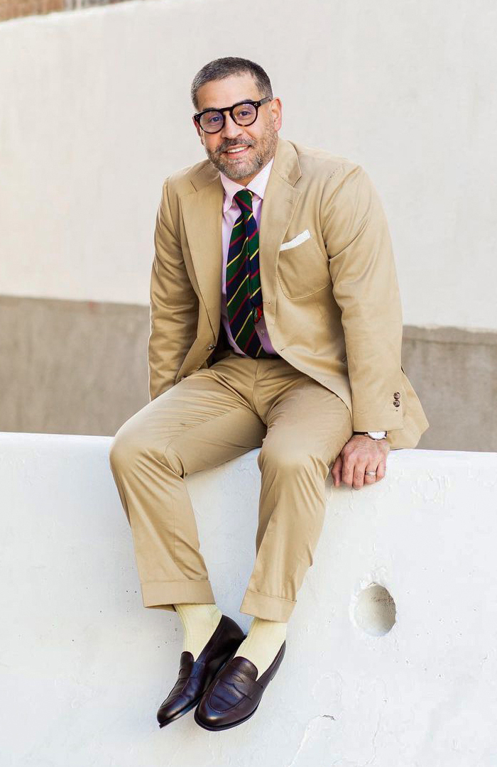 Tan suit with light pink shirt and navy/green striped tie