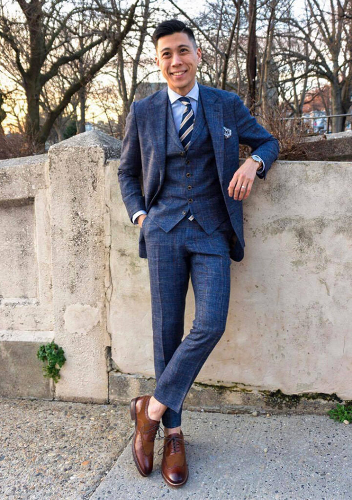 Three-piece blue plaid suit with a blue shirt, navy striped tie, and brown brogues