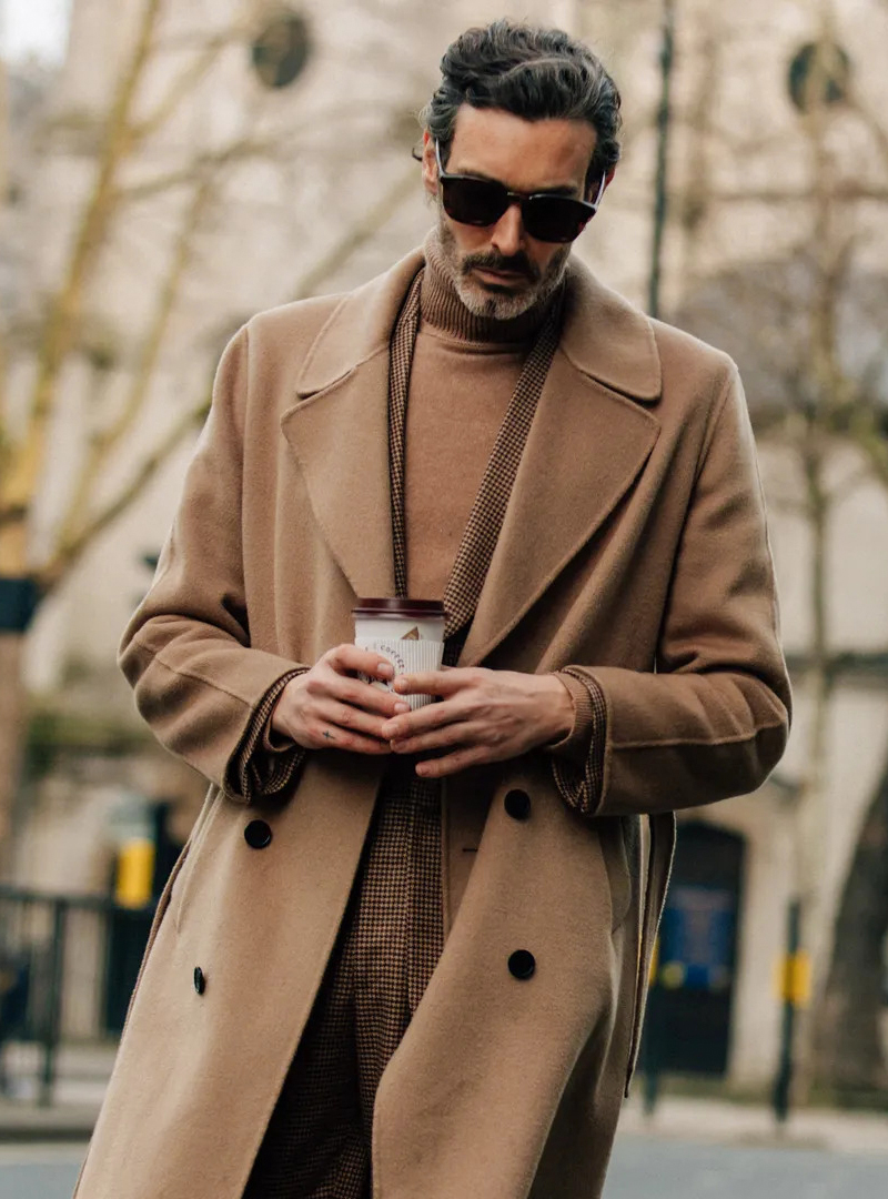 Wearing a brown overcoat and patterned blazer