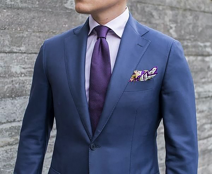 Wearing a navy blue suit with a lilac shirt and a dark purple tie