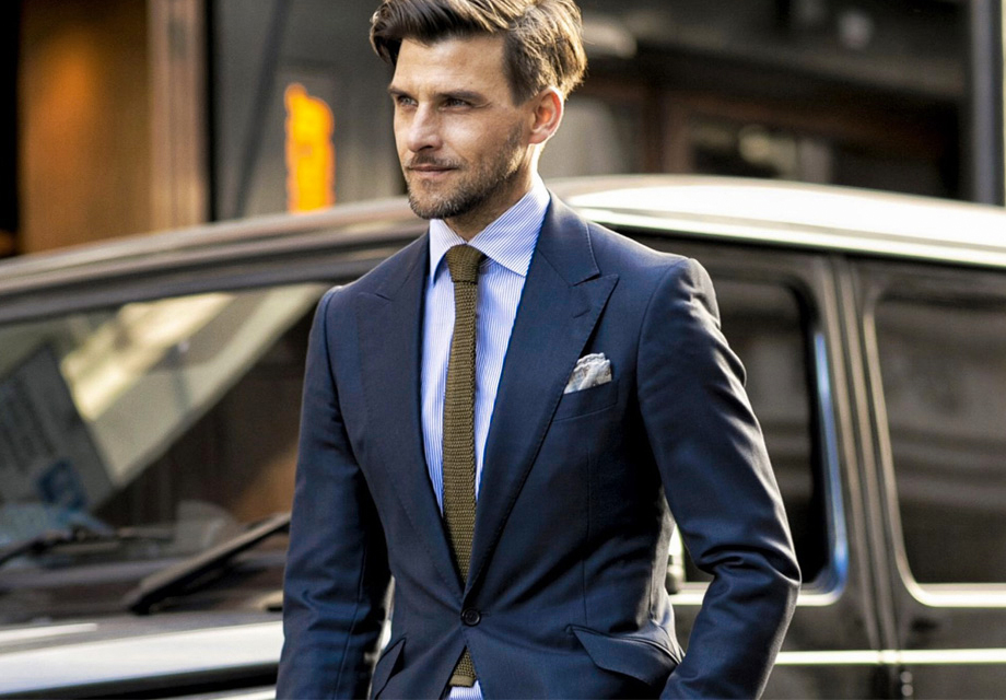 Wearing a navy suit with a blue striped shirt and brown tie