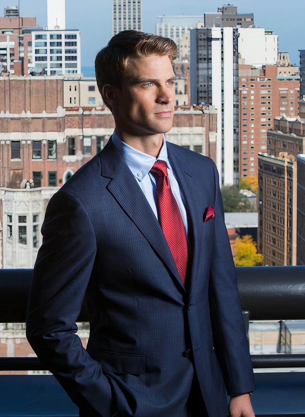 Wearing a navy suit with light blue shirt and red tie