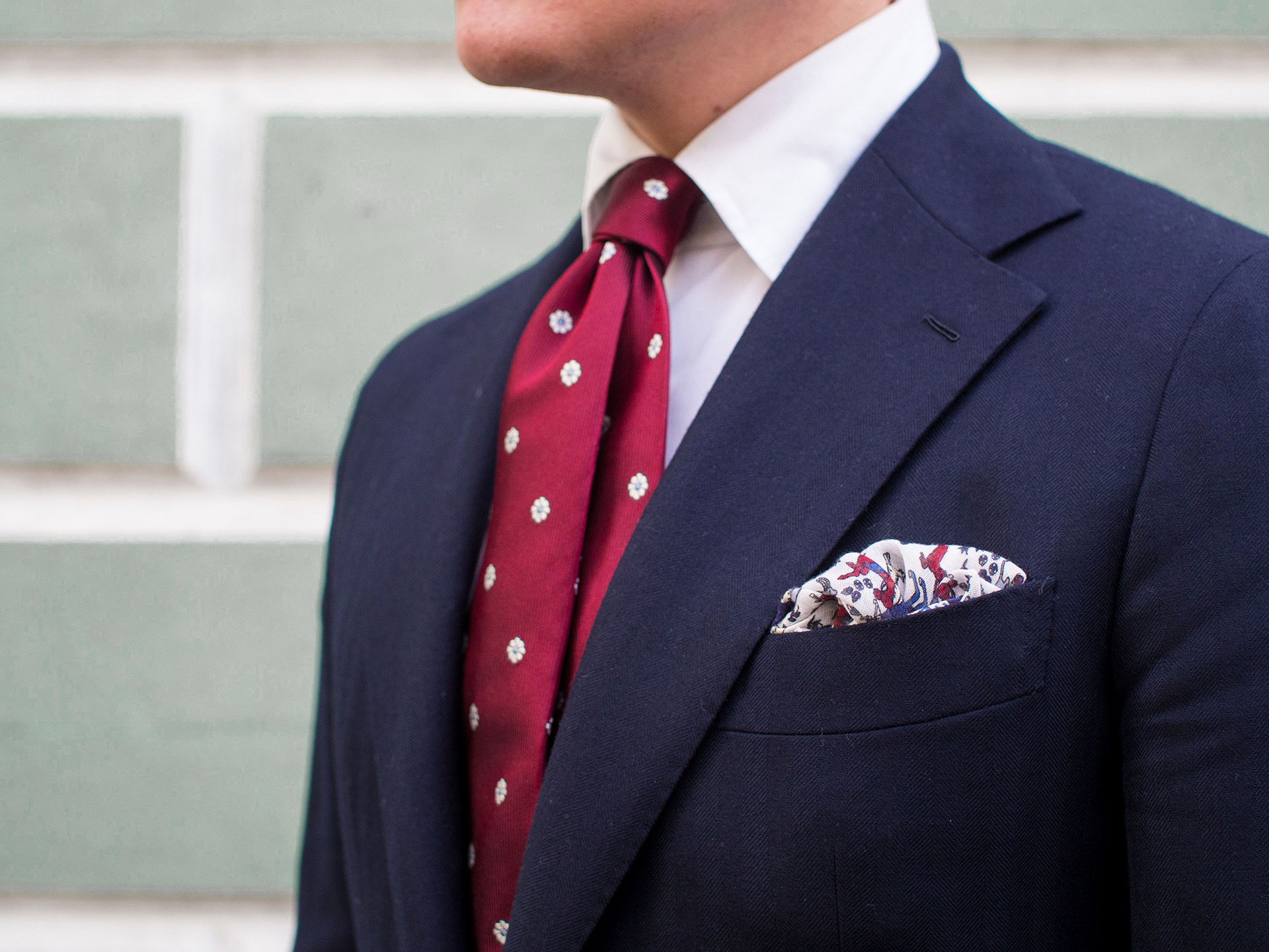 Wearing a navy suit with a white shirt and polka red tie