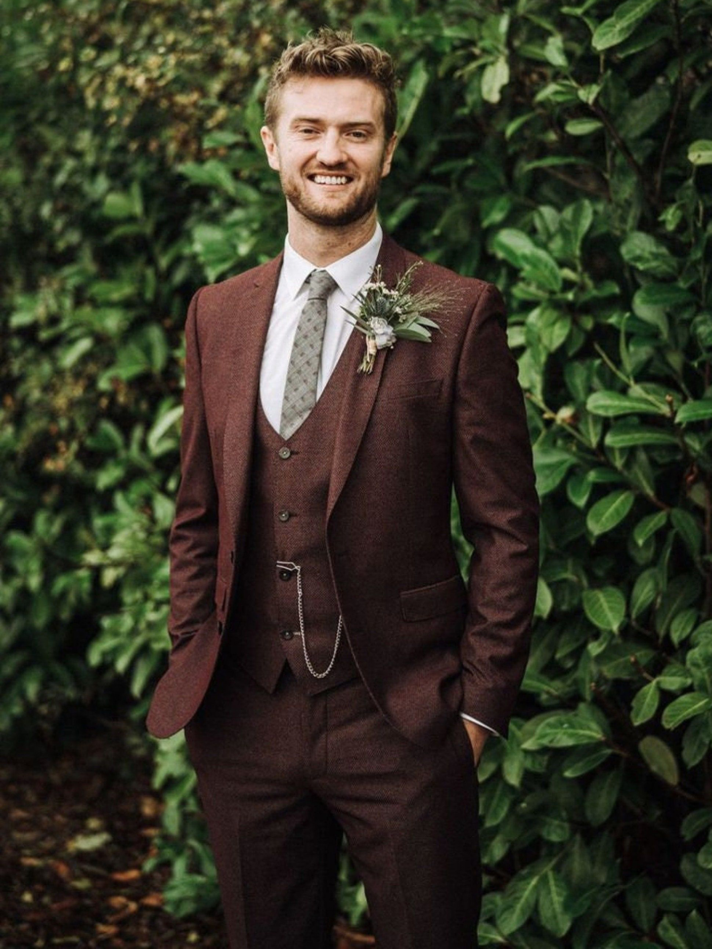 Wearing a maroon suit with a white shirt and olive tie at a wedding